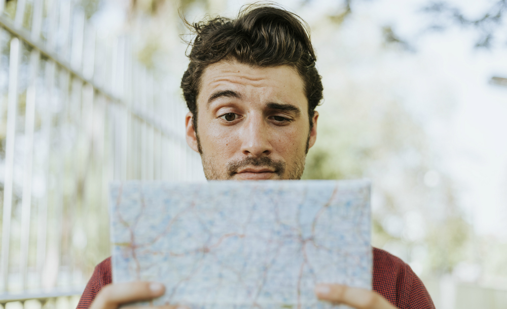 Foto de um homem olhando para um mapa, com uma das sobrancelhas arqueadas.