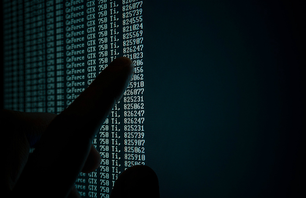 Foto de uma pessoa apontando para uma tela de computador cheia de números.